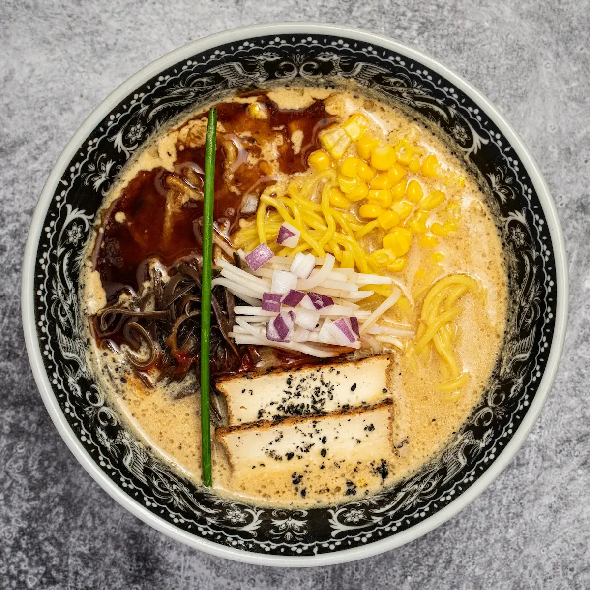 Vegan Miso Original - A bowl of miso and sesame broth ramen with thick noodles, tofu chashu, black garlic oil, bean sprouts, corn, kikurage mushrooms, and umami paste